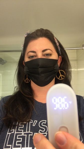 A masked member of touring staff takes her temperature, that reads 98.6 degrees.
